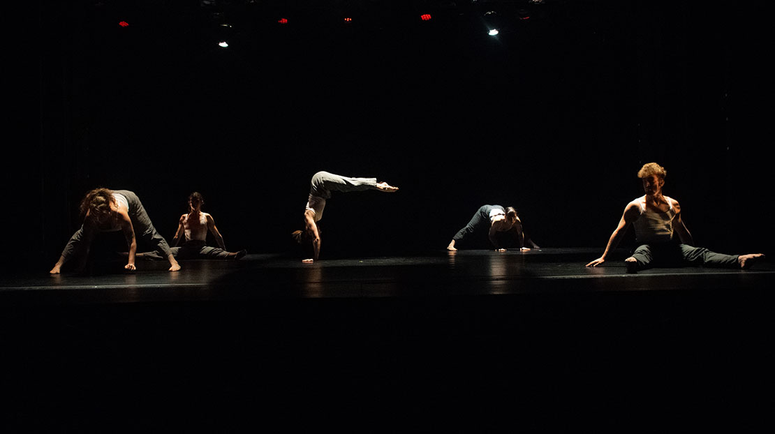 Five dancers execute floorwork in individual pools of light in Dicey, choreographed by Webster Dance alum Paige Van Nest.