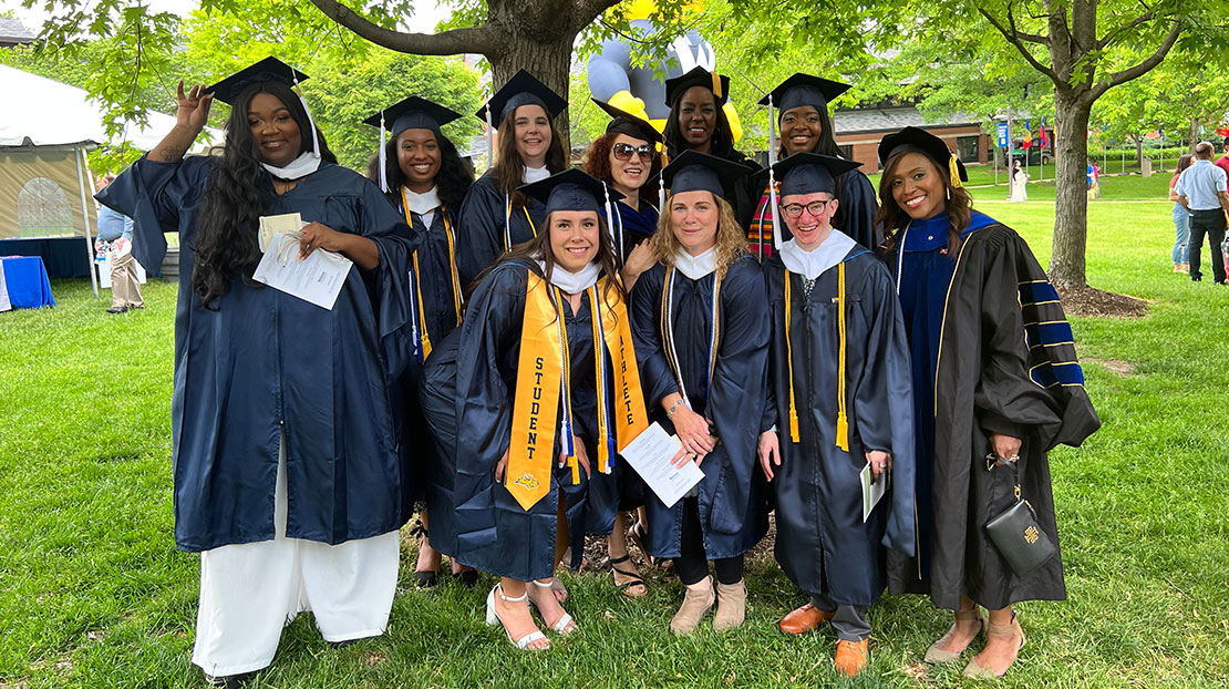 WICS Scholars graduates and professors pose with caps and gowns.