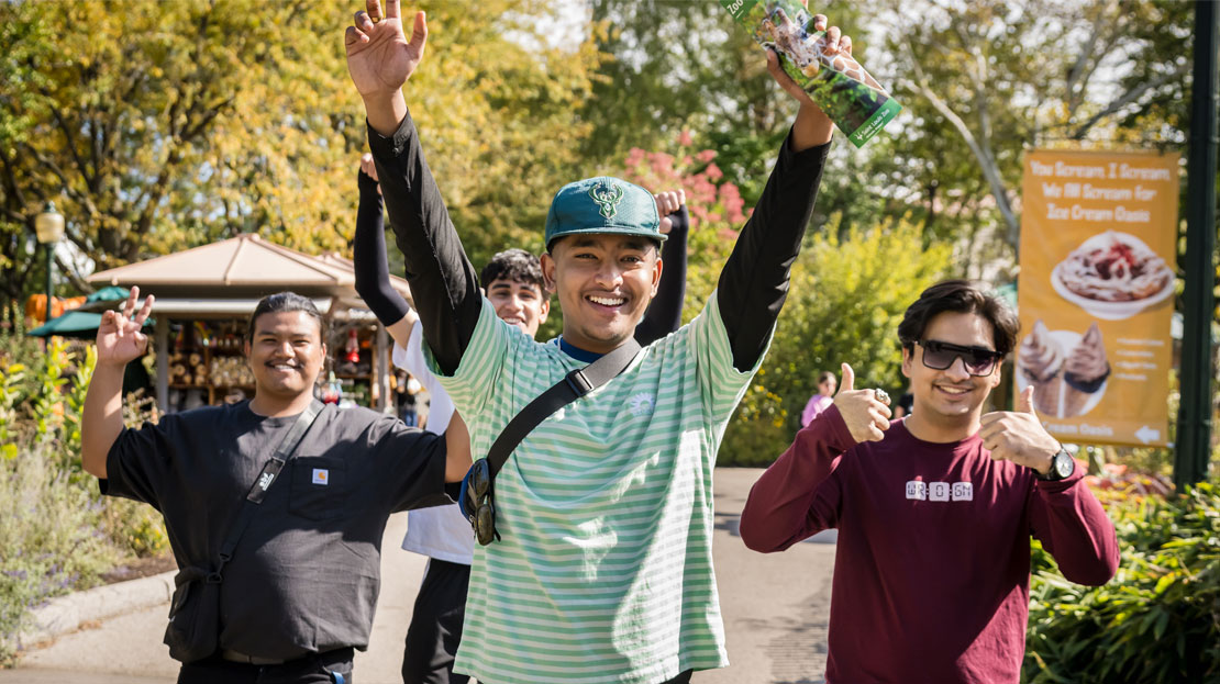 A small group of Webster students smile and gesture excitedly during an International Student event.