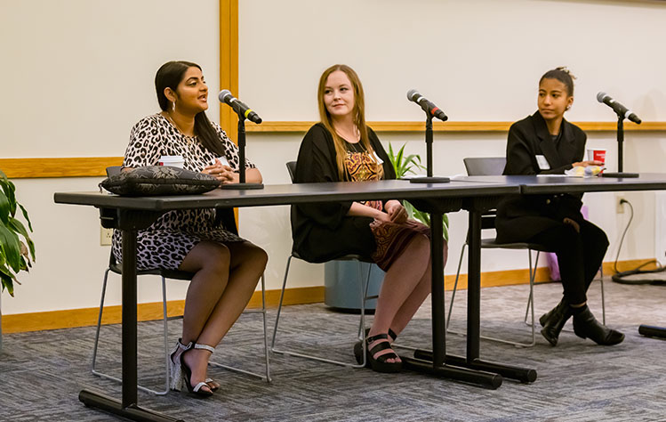 Three student's sit in the front of Sunnen Lounge presenting at the Big Questions series.