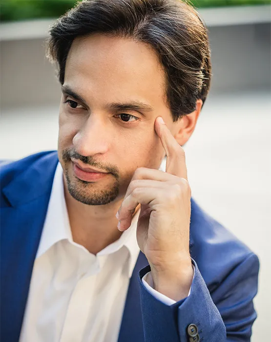 Darwin Aquino wearing white shirt and blue blazer, leaning on hand