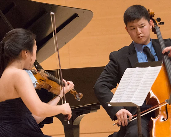 A pair of students playing string instruments.