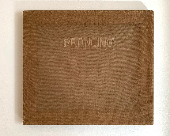 A textured, brown piece of fabric stretched over a canvas with the word "Prancing" in capitalized, typewriter-style lettering in a lighter shade of brown.