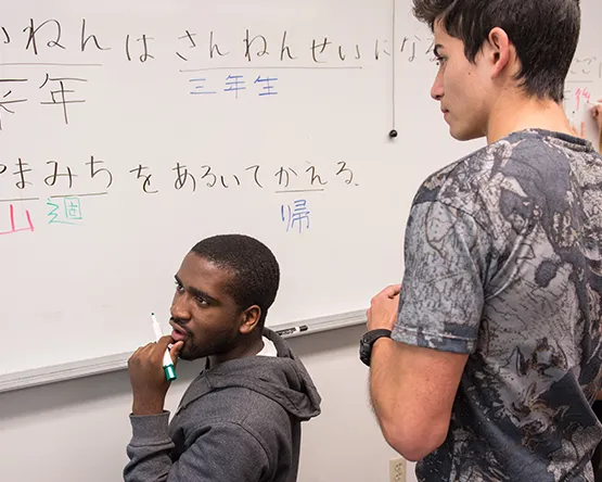 Students write Japanese on whiteboard in class