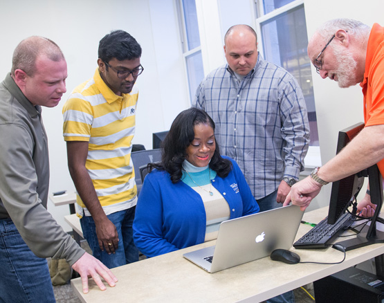 students talking around laptop