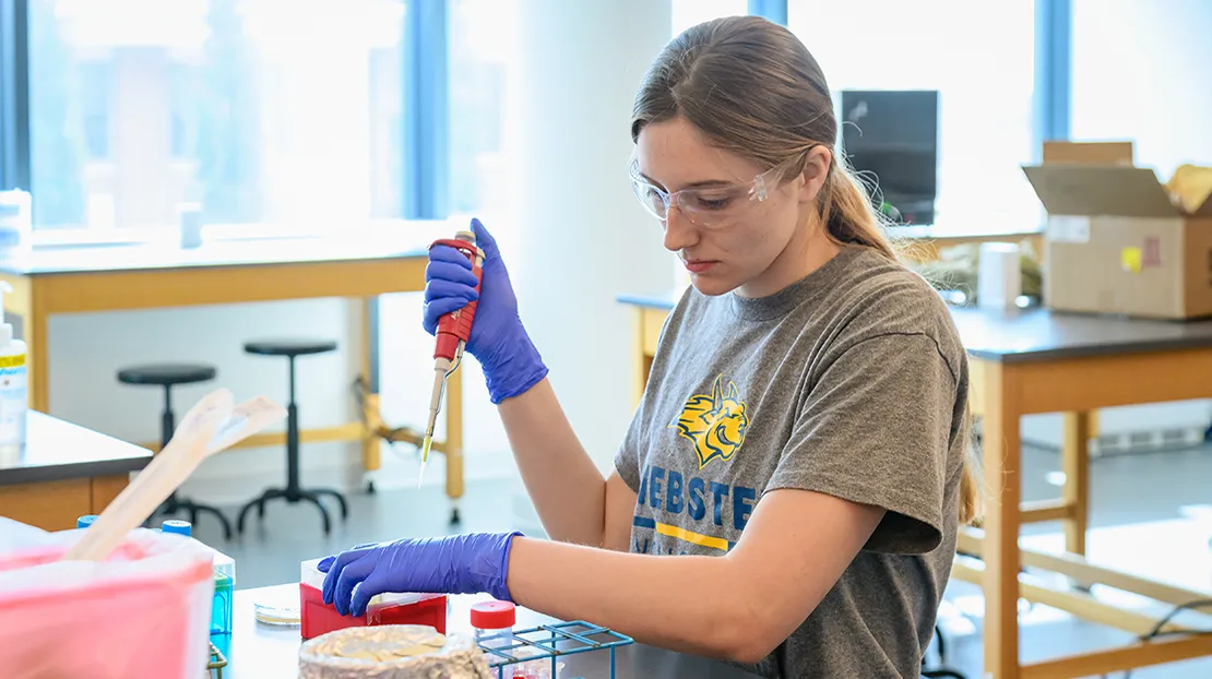 Nursing student in a lab setting working with a syringe.